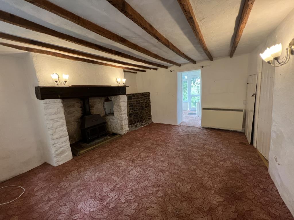Lot: 115 - COTTAGE FOR REFURBISHMENT WITH LARGE GARDEN AND PARKING, PLUS SEPARATE PADDOCK - View of the living room from the entrance porch